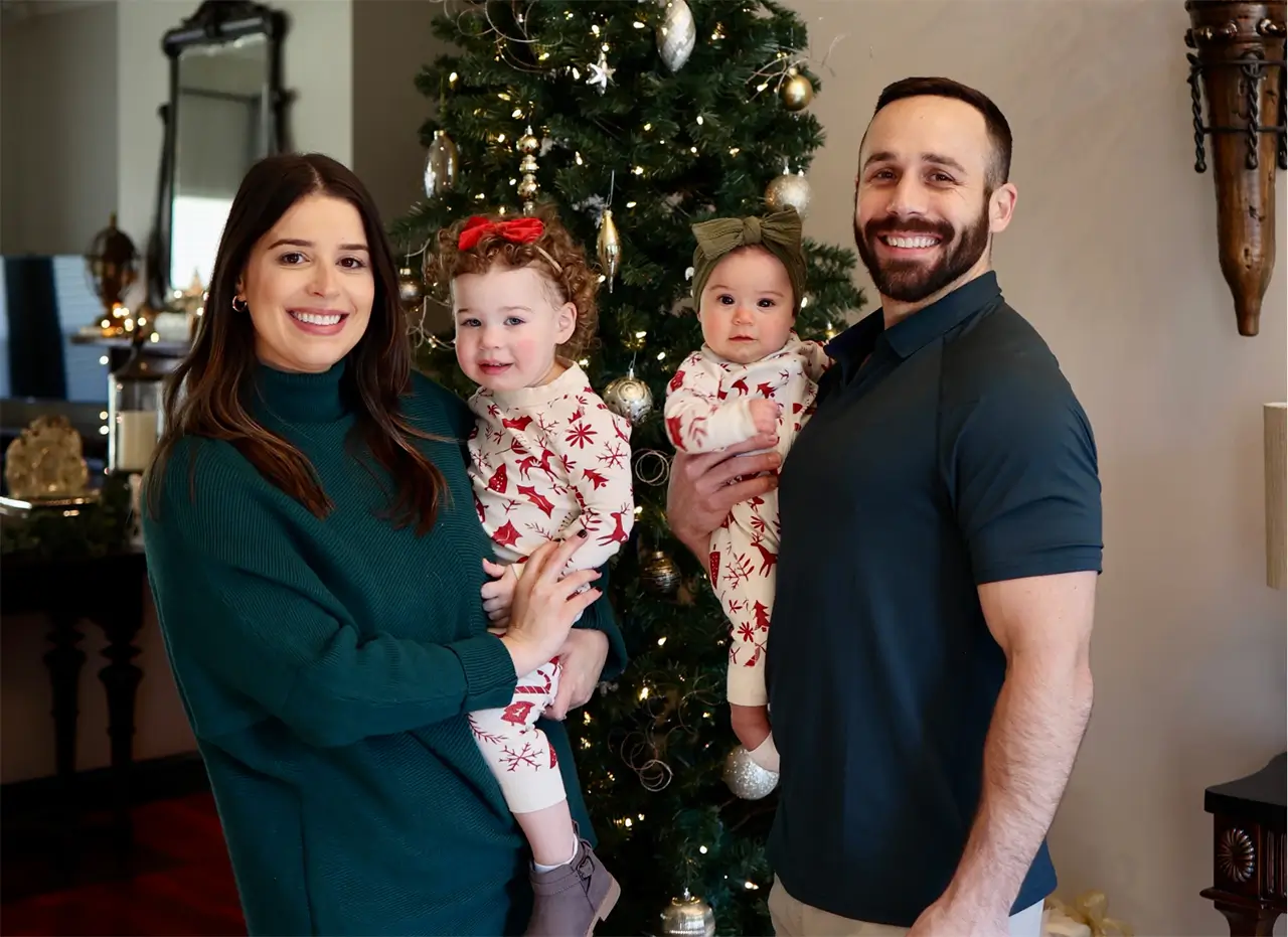 An image of a family gathered closely taking a picture near a Christmas tree